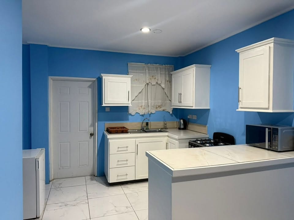 Kitchen and breakfast bar with a fridge, microwave, gas cooker and tiled floor.