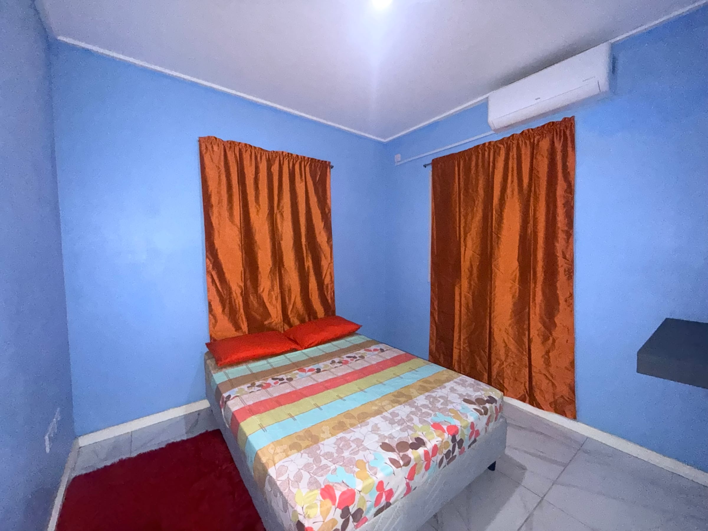 Bedroom with a full-size double bed, air conditioning and curtained windows.