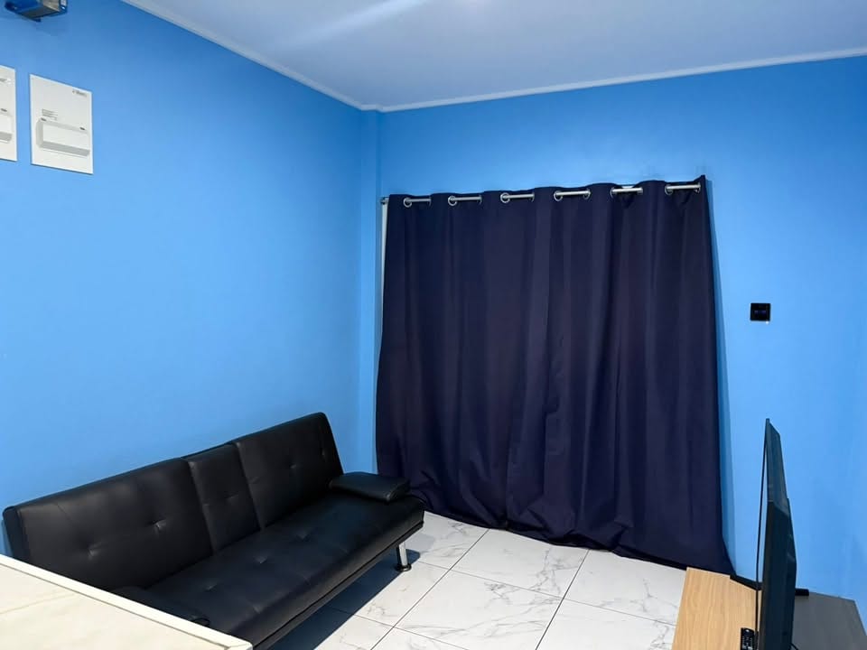 Living room with a sofa bed, a television and blackout curtains.